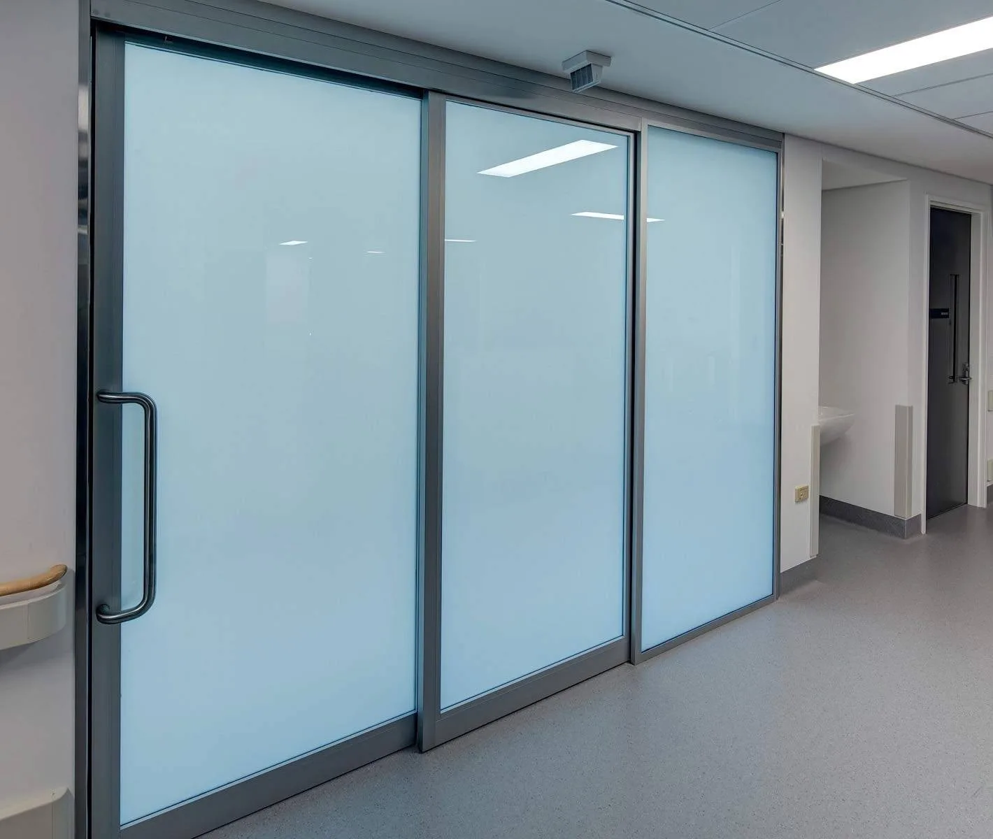 The same hospital corridor partition switched to privacy, the glass an even white