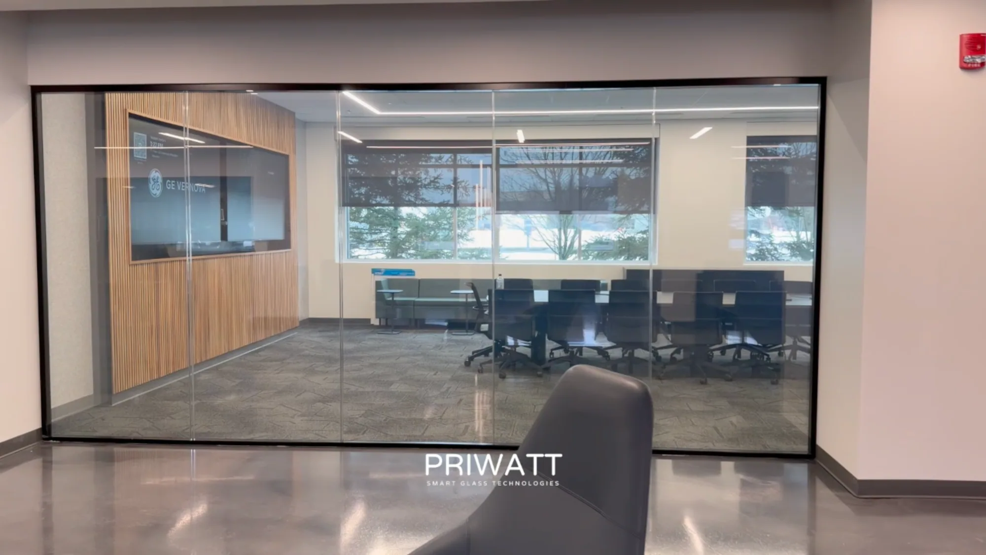 A GE Vernova office wall in PriWatt smart glass, clear, the desks beyond visible through it