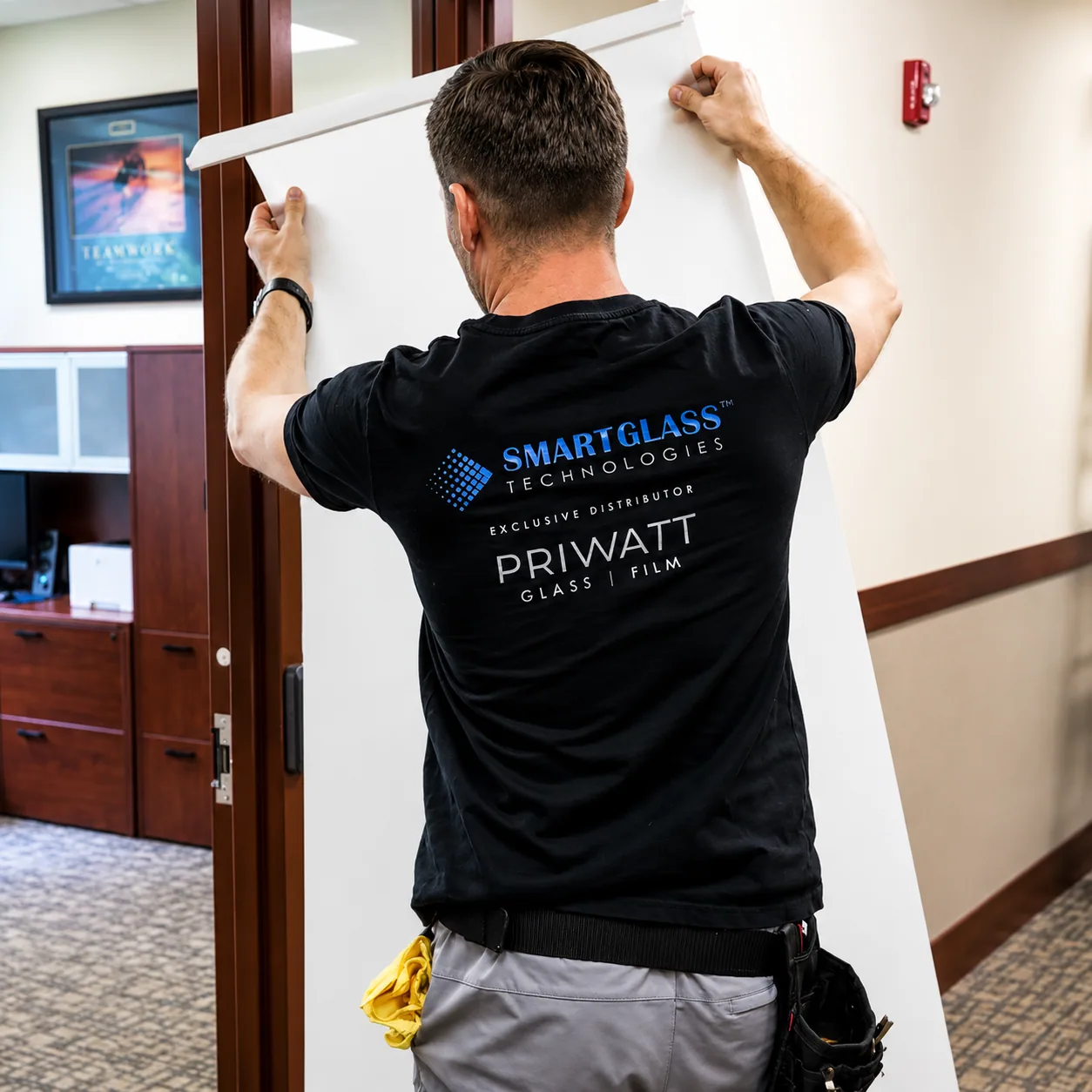 PriWatt technician carrying a sheet of switchable smart film on site