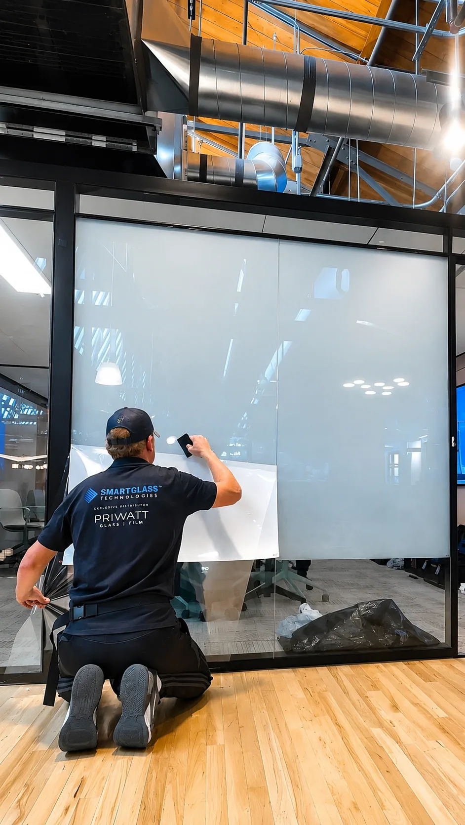 PriWatt technician installing switchable smart film onto a glass panel
