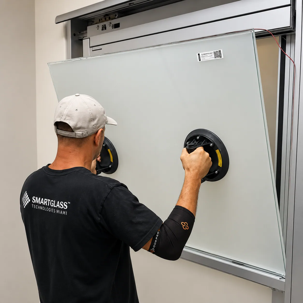 PriWatt technician positioning a smart glass panel with a suction handle