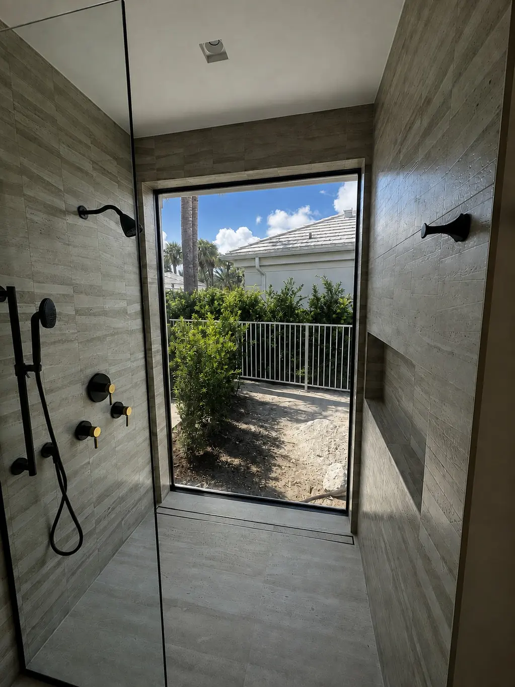 A walk-in shower with a full-height window in PriWatt normal-mode switchable glass, clear — the planting, a railing and the sky beyond it