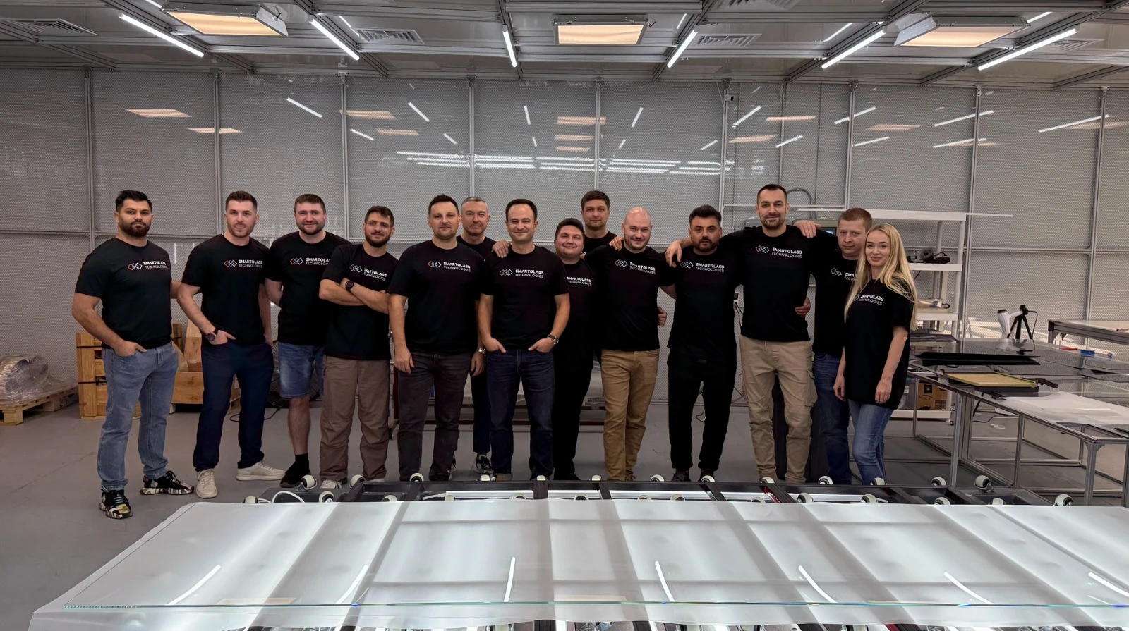 The Smart Glass Technologies team on the production floor, behind a run of switchable panels